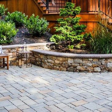 Cozy backyard patio with stone flooring and curved stone wall seating.