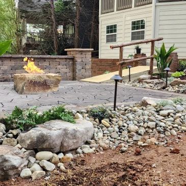 Cozy backyard patio with fire pit and decorative rocks.