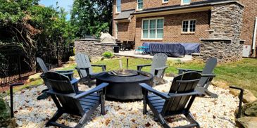 Outdoor fire pit surrounded by six chairs in a backyard.