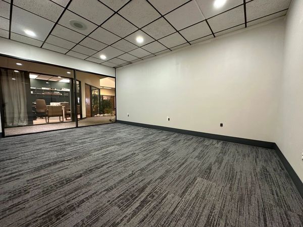 Empty office room with carpet flooring and glass partition.