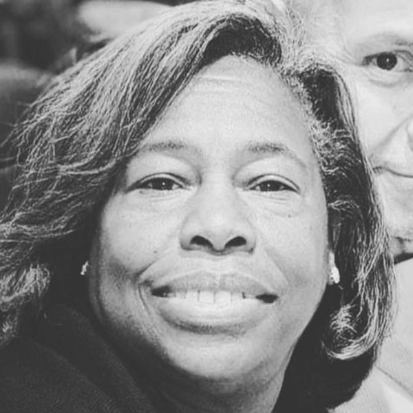 Close-up of a smiling woman with natural hair in black and white.