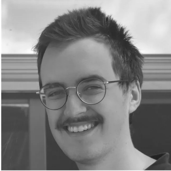 A smiling man with glasses and a mustache in black and white.