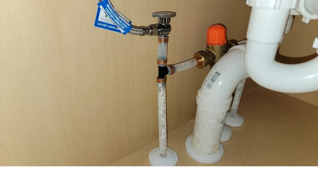 Close up of a water supply plumbing system underneath a sink.