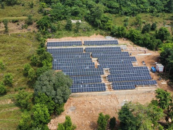A solar panel array installed in a clearing surrounded by greenery.