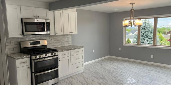 Modern kitchen with white cabinets and stainless steel appliances.