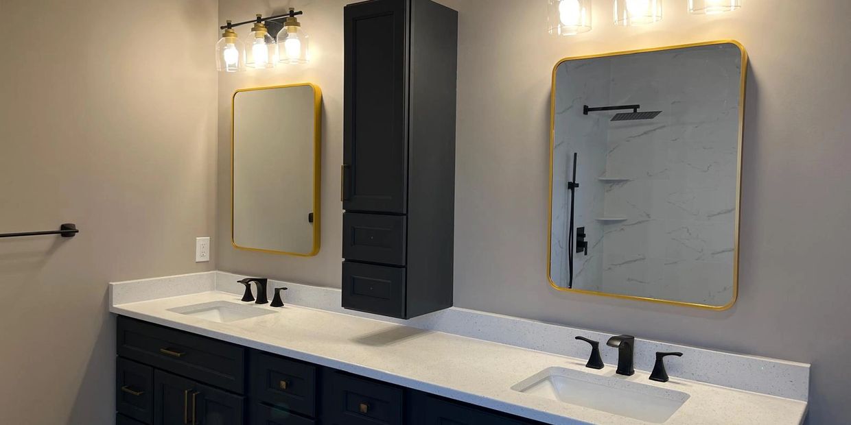 Modern bathroom with dual sinks, gold-framed mirrors, and black cabinetry.