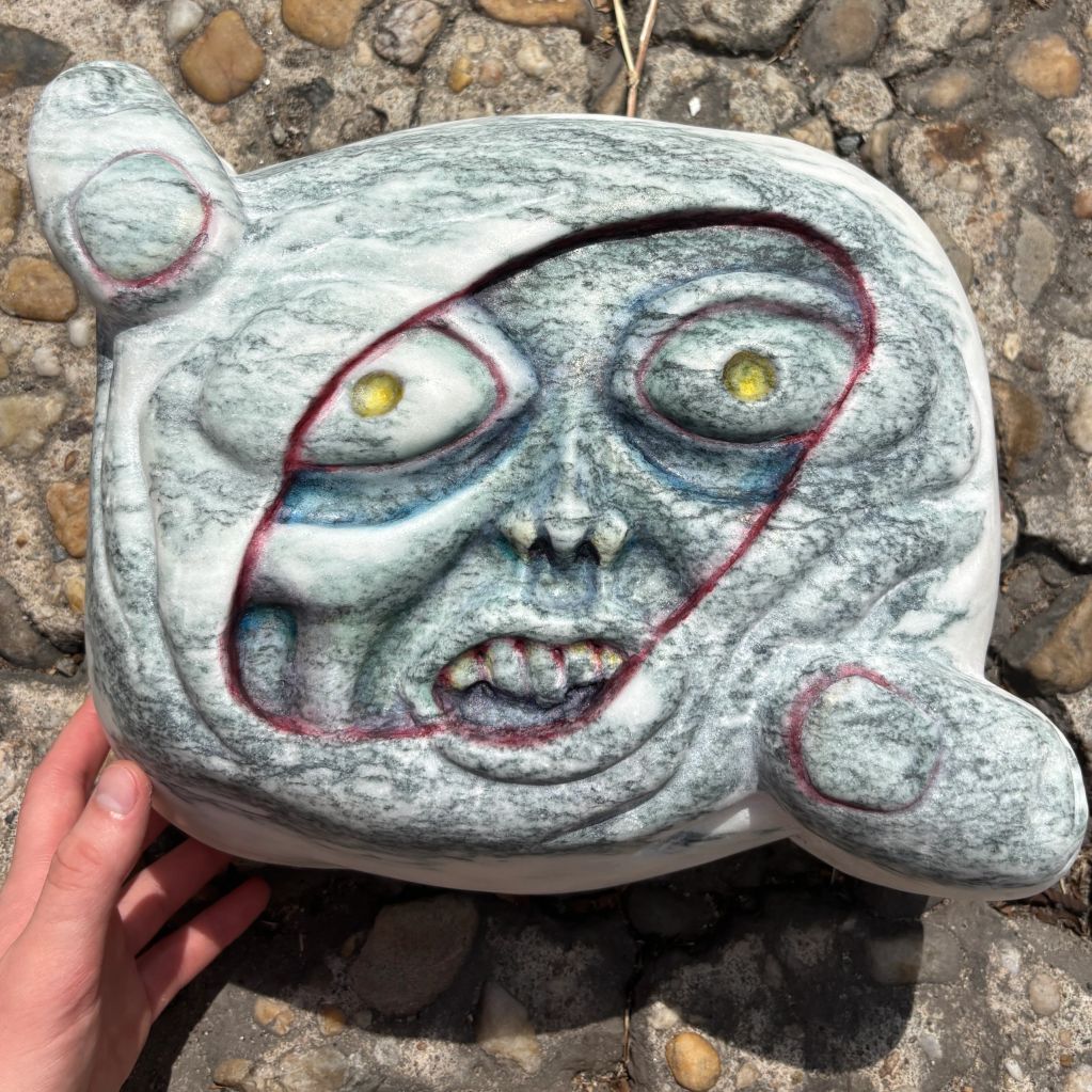 Marbled stone sculpture with a grotesque face.