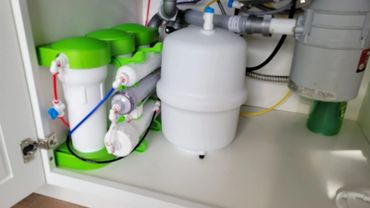 Under-sink water filtration system with green and white components.