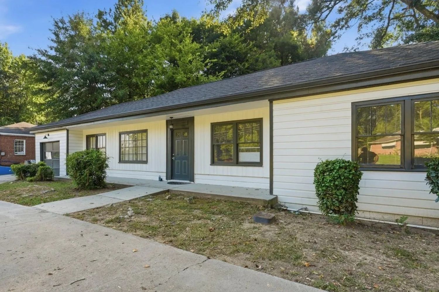 Single-story white house with green-trimmed windows and door.