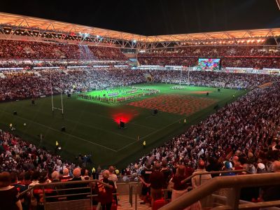 Large rugby stadium filled with spectators at night.