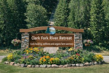 Rustic entrance sign at Clark Fork River Retreat with flower gardens, offering renewal, and peace.