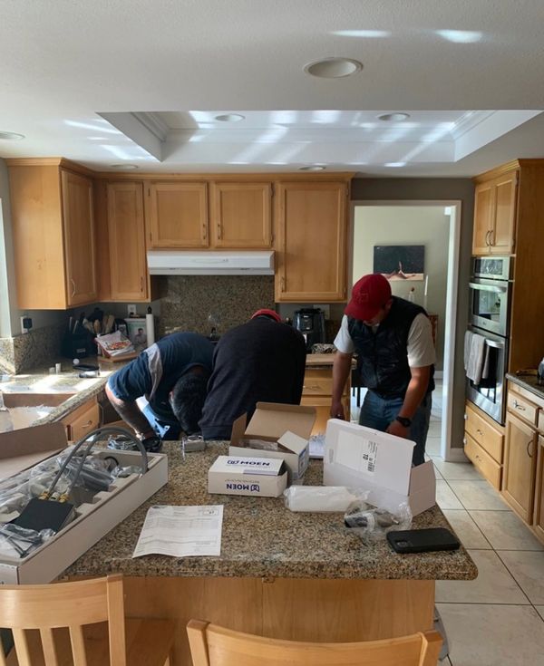 Client photo of our staff installing client's new kitchen faucet.