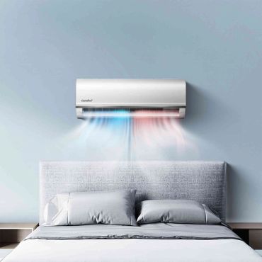Air conditioner blowing cool and warm air above a bed.