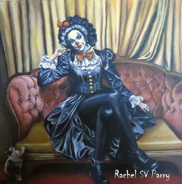 A gothic pin-up clown sits on a couch while her cat claws up the corner.
