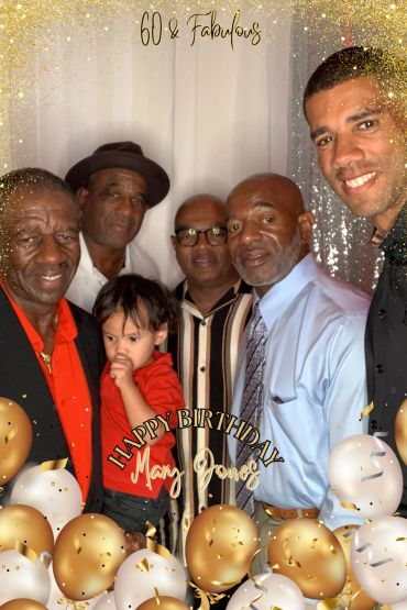 Family celebrating Mary Jones' 60th birthday with gold and white balloons.