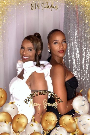 Two elegant women celebrating Mary Jones' 60th birthday with gold and white balloons.