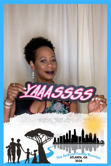 Woman holding "YAAASSSS" sign at Jackson Family Reunion 2026.