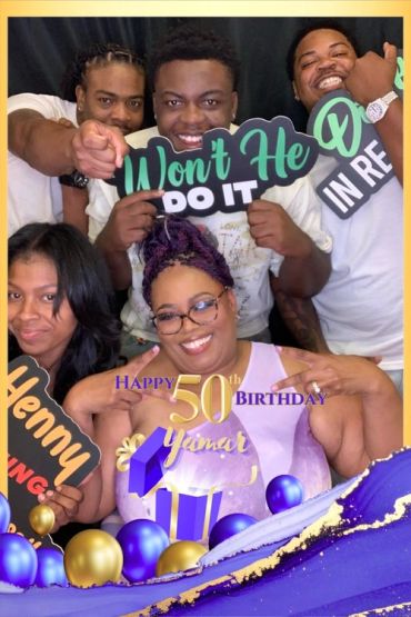 Group celebrates a 50th birthday with smiles and signs.