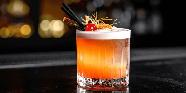 Elegant cocktail with a cherry garnish and foam top.