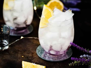 Glass of iced lavender lemonade with lemon wedge.