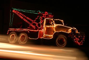 Tow truck decorated with colorful Christmas lights at night.