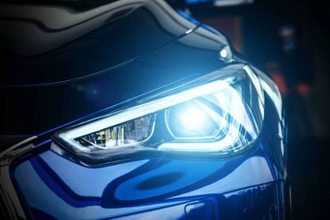 Close-up of a bright blue car headlight illuminated at night.