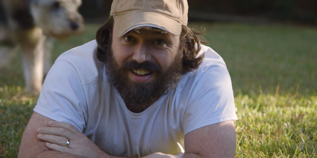 Andy LaViolette and his dog laying in green grass introducing Life at the House DIY videos.