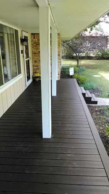Clean wooden porch with white pillars and garden view.