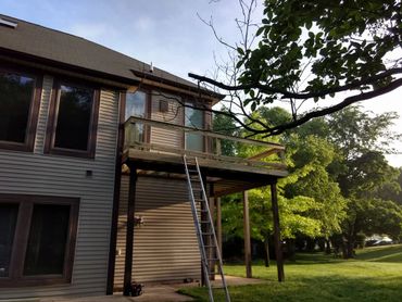 A house with a newly built wooden balcony and a ladder leaning against it.