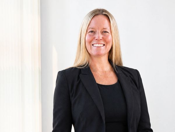 Smiling woman in black blazer and top.
