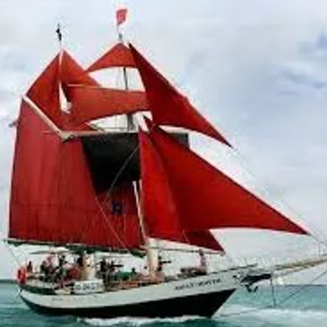 Sailing ship with red sails on the sea.
