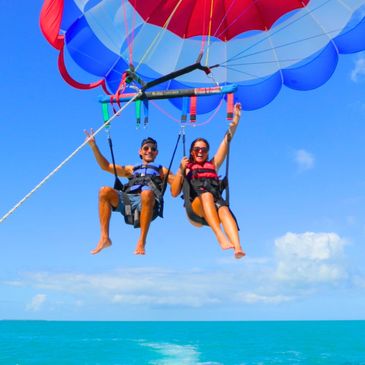 Couple parasailing over bright blue ocean.