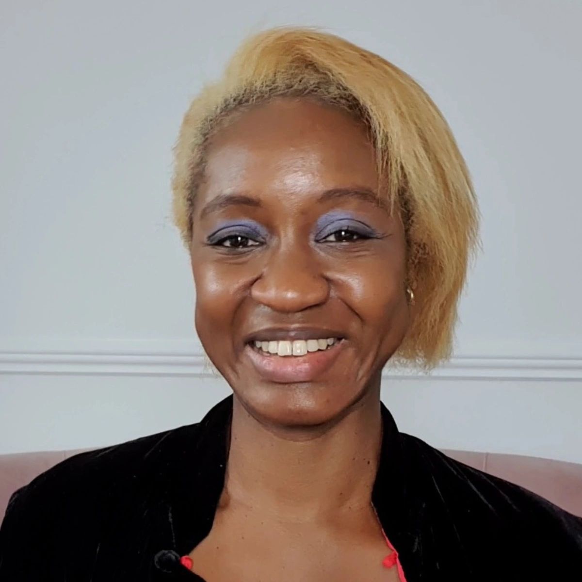 Black woman with blond hair smiles at camera