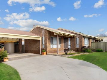 Single-story brick house with carport and well-kept lawn.