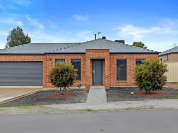 Simple brick house with garage and two trees.
