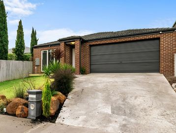 Brick house with a black garage door and a sloped driveway.