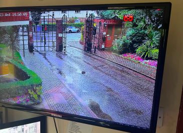 View of gated residential entrance seen on a security monitor.