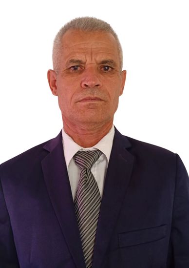 Portrait of a serious man in a dark suit and striped tie against a white background.