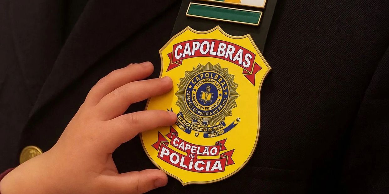 Hand holding a yellow police badge labeled CAPOLBRAS and CAPELÃO DE POLÍCIA.