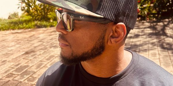 Man wearing sunglasses and cap looking to the side.
