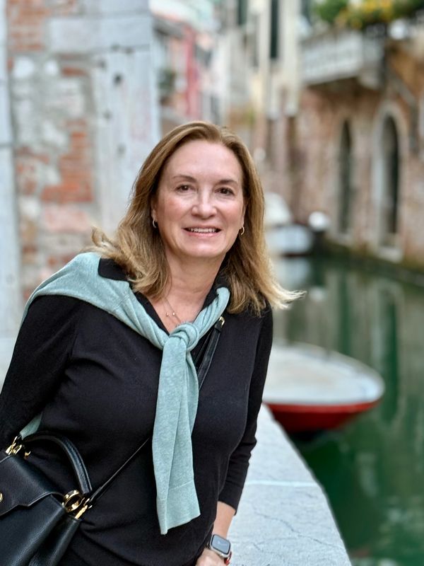 Smiling woman by a canal in a European city.