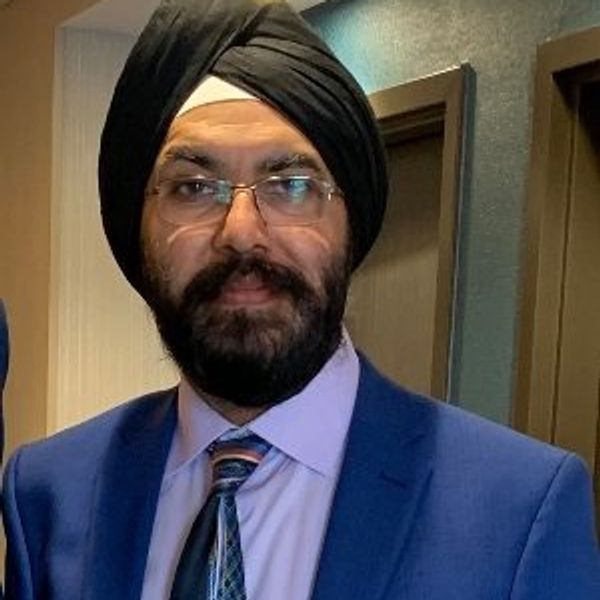 Man wearing a blue suit, glasses, and a black turban.