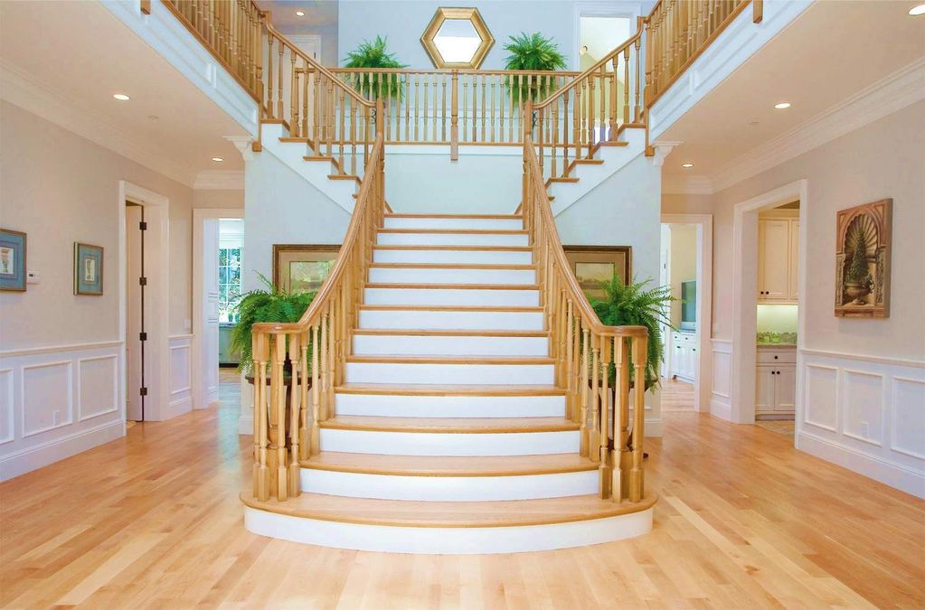 Dramatic foyer with custom white oak bifurcated staircase with elegant, curved balustrade system.