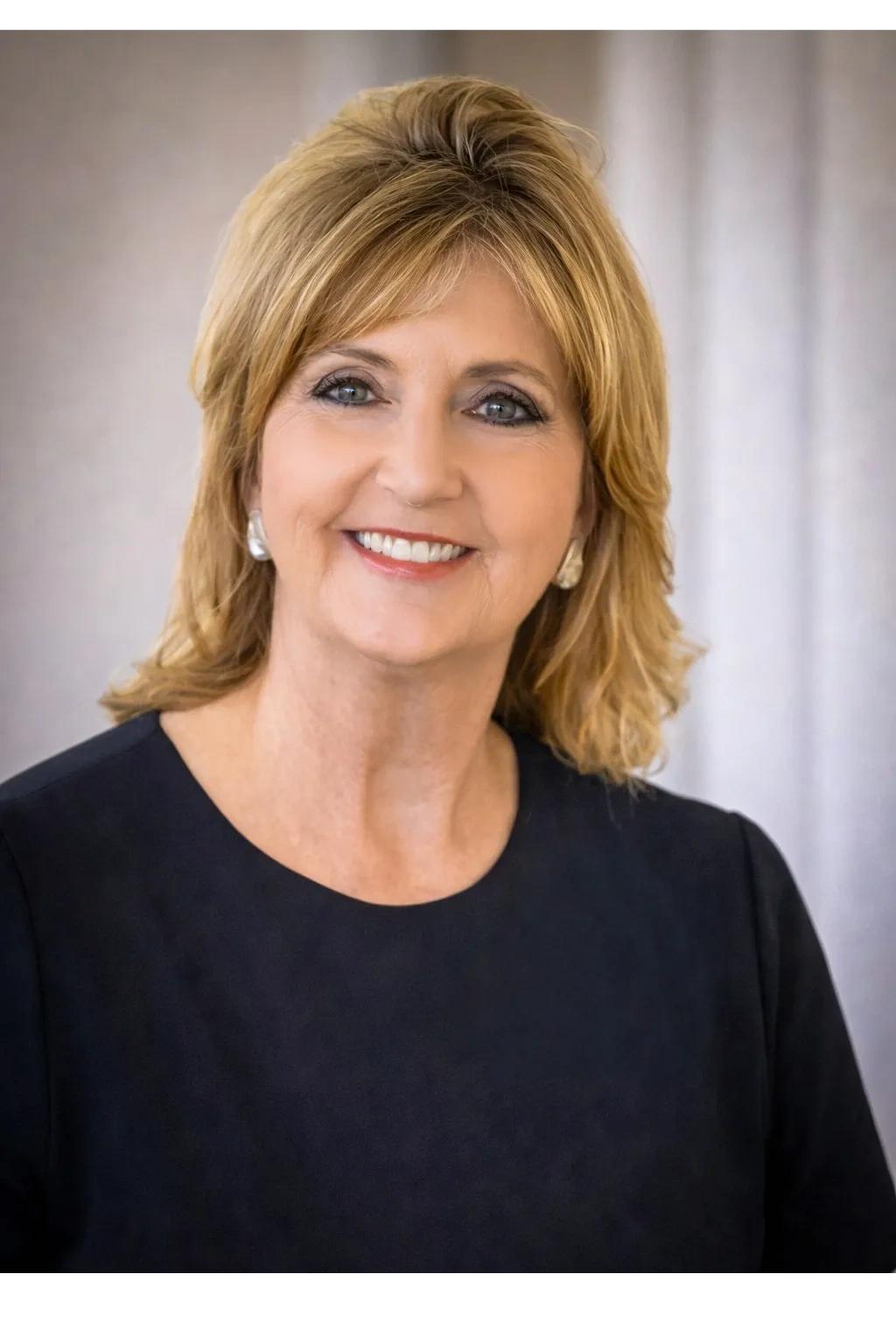 Smiling middle-aged woman with blonde hair in a black top.