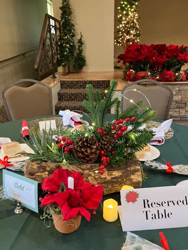 Table centerpiece with boughs of holly, pine cones, and berries inside a hollowed out log.
