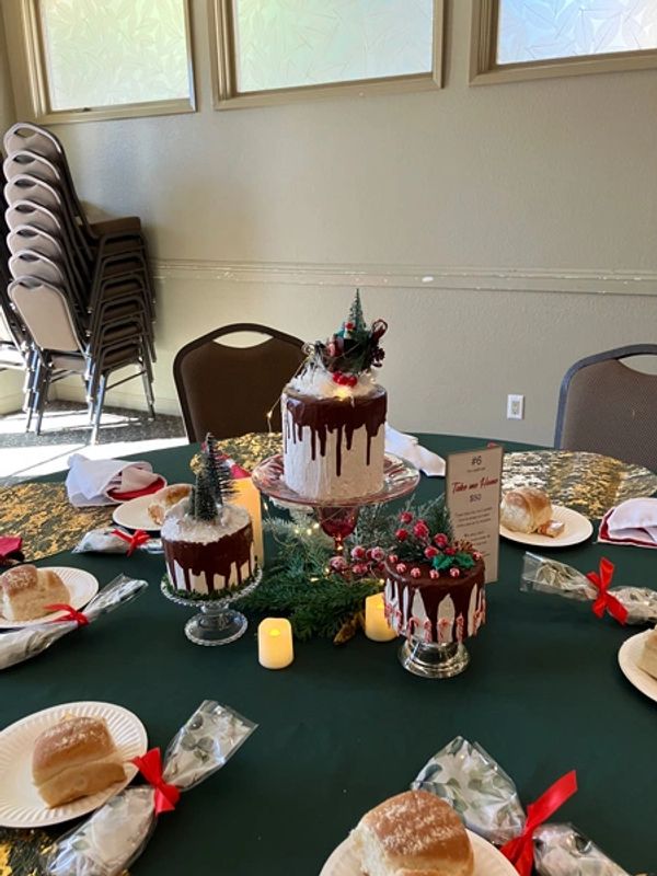 Holiday centerpiece with 3 white cakes with chocolate frosting and decorative tops with lit candles.