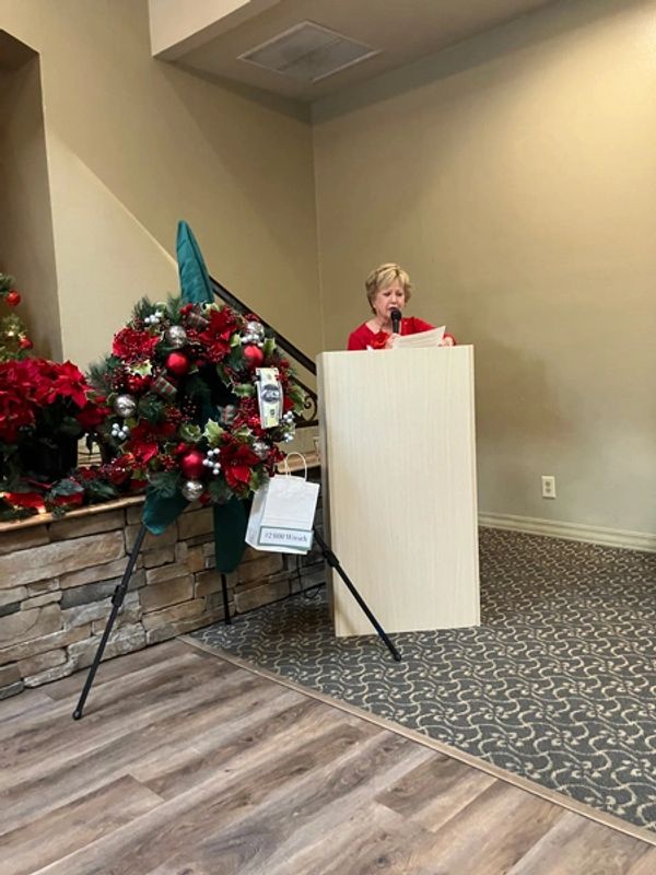 Holiday Luncheon 2024 speaker with decorative wreath.