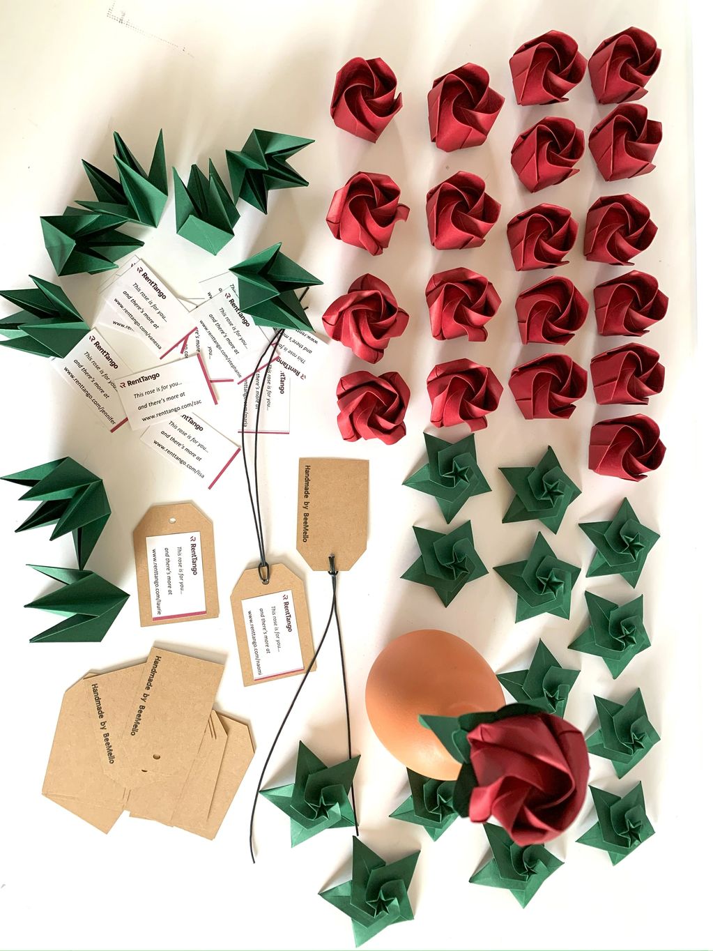 red origami roses being made as favors to corporate clients over a white table