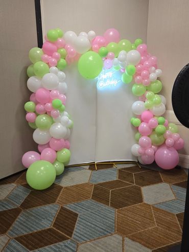 Colorful balloon arch with a glowing 'Happy Birthday' sign as a party backdrop.