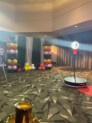 Photo booth setup with colorful balloon columns and ring light in an event space.